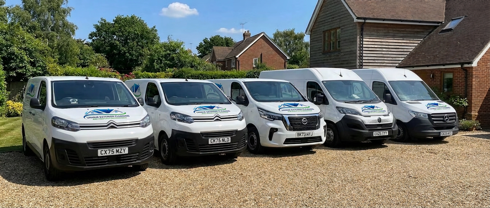 Five white vans with Unique Exterior Cleaning branding, digitally edited